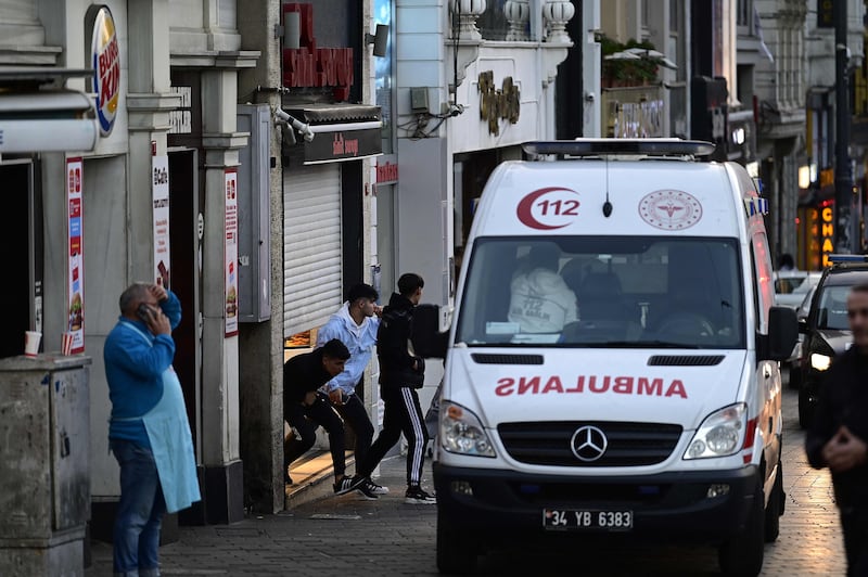 An ambulance passes people leaving a store. AFP