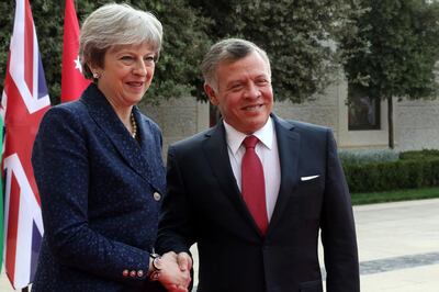 Britain's Prime Minister Theresa May (L) shakes hands with Jordan's King Abdullah II as he receives her at the royal palace in Amman on November 30, 2017. / AFP PHOTO / KHALIL MAZRAAWI