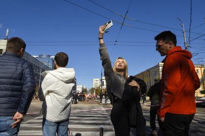 A woman using a mobile phone takes a selfie near the site of a missile strike in downtown Kyiv. EPA