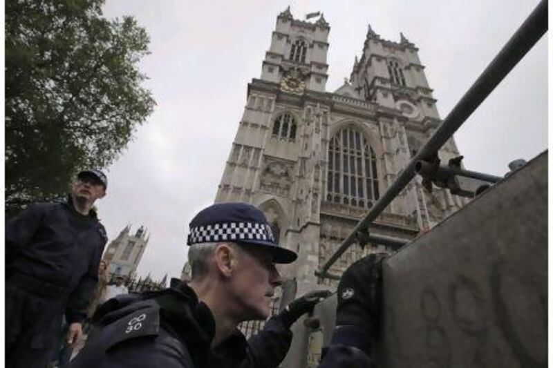 British police officers inspect tubes to be used to build a stage reserved for media outside the Westminster Abbey in central London.