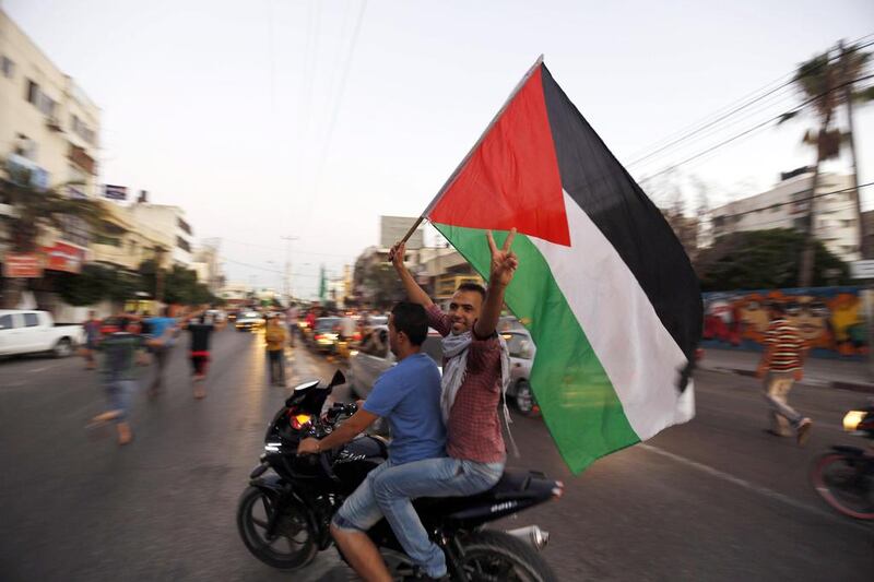Palestinians wave the national flag as they gather is the streets of Gaza City on August 26, 2014, to celebrate a long-term truce agreed between Israel and Hamas in the Gaza Strip. Mohammed Abed / AFP