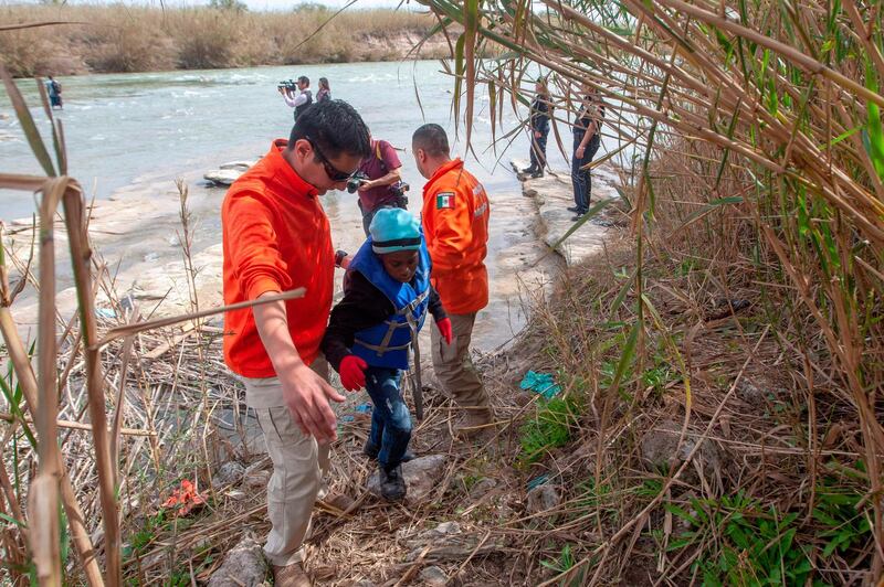 Members of the Beta group of Mexican National Institute of Migration, dedicated to the protection and defence of human rights of migrants, rescue a Honduran migrant child trying to cross the Rio Grande.  AFP