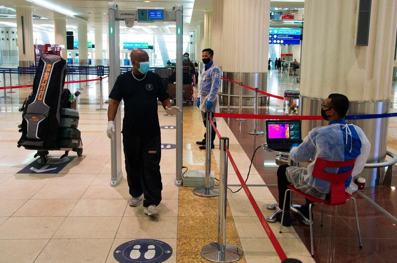 A passenger wearing a mask passes through a temperature screening at Dubai International Airport's Terminal 3 in Dubai. The coronavirus pandemic has hit global aviation hard, particularly at Dubai International Airport, the world's busiest for international travel, because of restrictions put in place to contain the virus. AP Photo