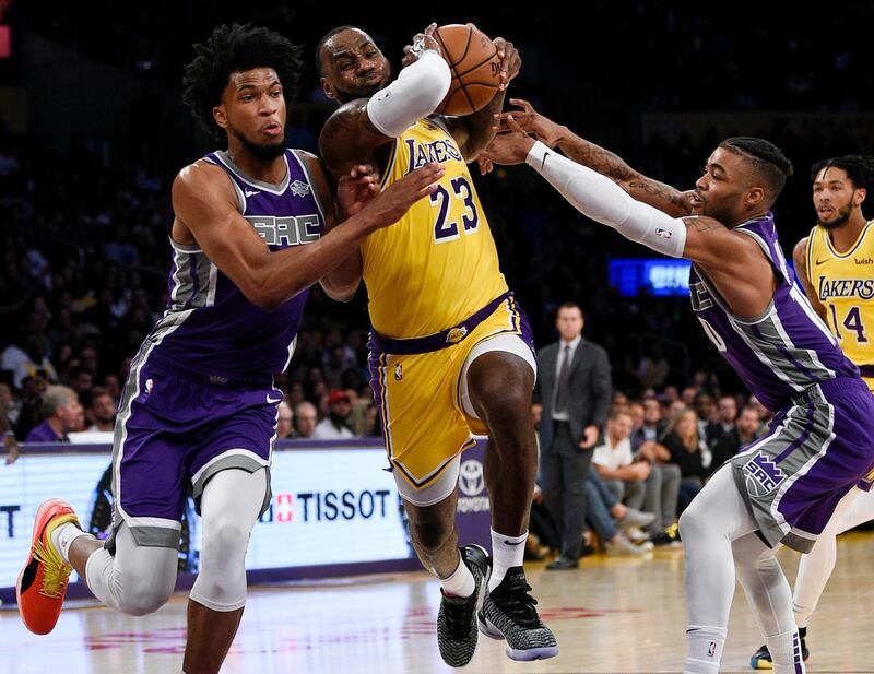 Los Angeles Lakers forward LeBron James, center, drives the ball between Sacramento Kings forward Marvin Bagley III, left, and guard Frank Mason III during the first half of an NBA preseason basketball game in Los Angeles, Thursday, Oct. 4, 2018. (AP Photo/Kelvin Kuo)
