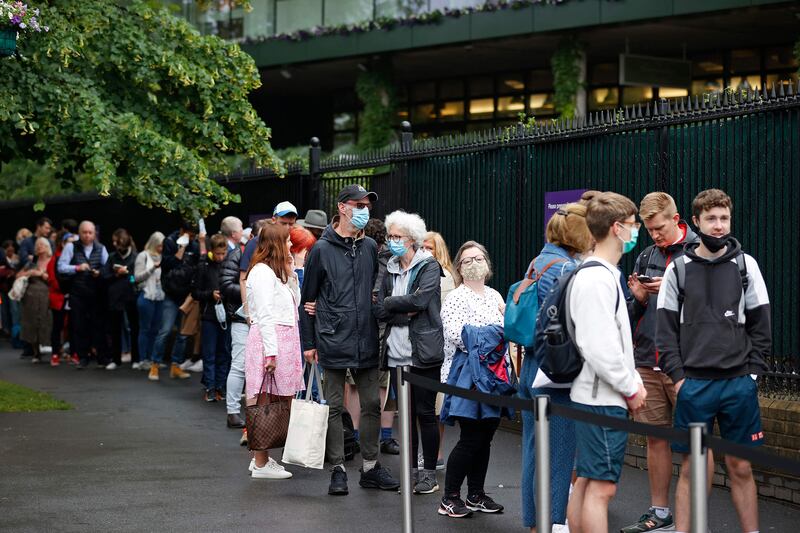 Spectators, some wearing face masks, queue to enter the grounds at the 2021 Wimbledon Championships.