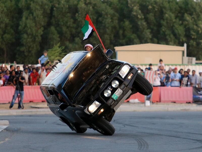 Dubai, May 31, 2013 - Haran Al Ghufli waves a UAE flag out of a Land Cruiser driven on two wheels by Mohammed Al Matlae at the Fast and Furious "Extreme Car Park" event at Studio City in Dubai, May 31, 2013. (Photo by: Sarah Dea/The National)

