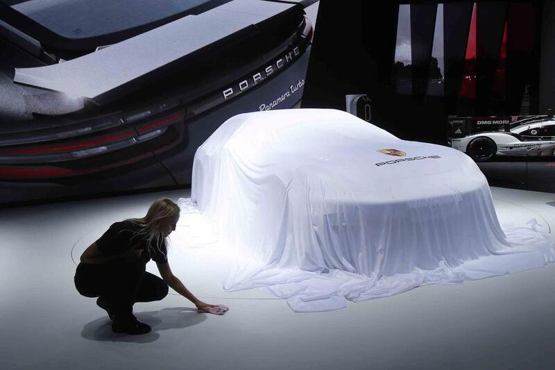 A worker adjusts the sheet around a car at the Porsche stand during the Paris Motor Show in Paris. Michel Euler / AP