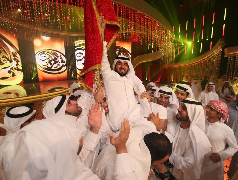 Saif Al Mansouri, centre, celebrates with the winner’s crimson flag at the Million’s Poet award ceremony in Abu Dhabi on Wednesday. Karim Sahib / EPA