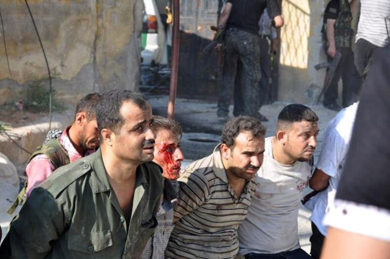 Free Syrian Army opposition fighters detain policemen, one of them wounded in the face, after overrunning the Shaar district police station in the northern Syrian city of Aleppo on July 25, 2012. Battles raged through the night in several districts of Syria's second largest city to which the regime had rushed reinforcement, after rebels launched an all-out assault for control of the country's commercial hub on July 20.   AFP PHOTO / PIERRE TORRES

