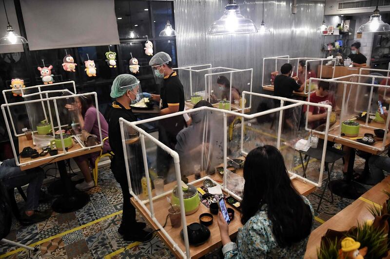 People eat in between plastic partitions, set up in an effort to contain COVID-19  at the Penguin Eat Shabu hotpot restaurant in Bangkok.  AFP