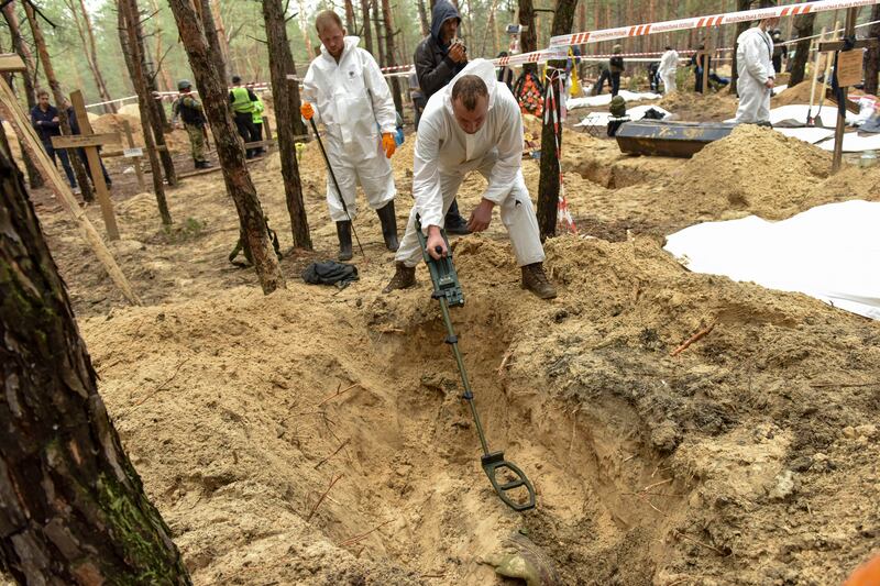 A forensic technician uses a metal detector during the exhumation of bodies from hundreds of graves discovered near Izium in north-eastern Ukraine after Russian forces were driven out. EPA