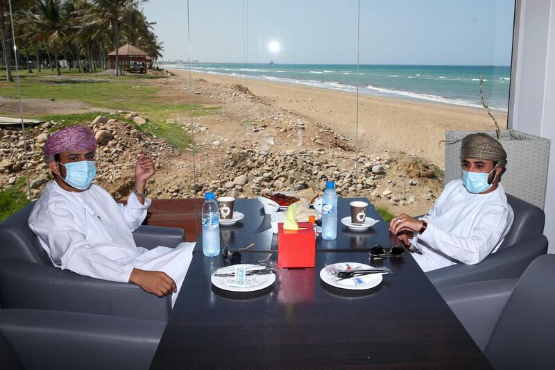 Omanis, wearing protective face masks, sit in a seafront cafe in the capital Muscat, during the coronavirus pandemic.  AFP