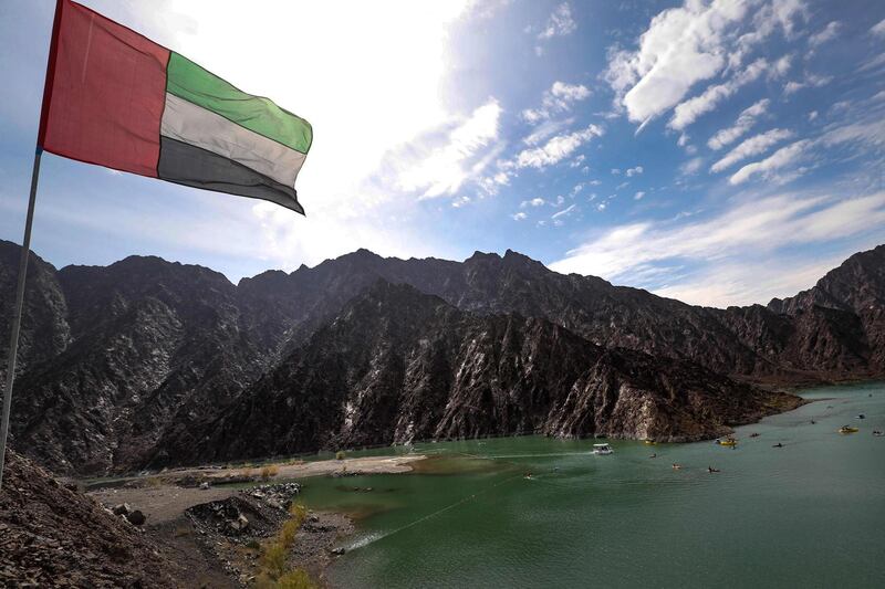 An Emirati national flag flying over the reservoir at the Hatta Dam where kayaks and boats are cruising near the Omani border.  AFP
