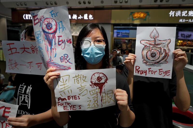 People hold signs which read "Black Police, Return eye," bottom centre during a protest at the arrival hall of the Hong Kong International airport in Hong Kong.  AP