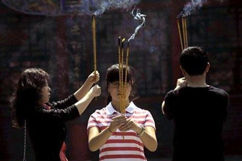 A family holds burning incense as they pray for the daughter's success in the upcoming National College Entrance Exam at a Taoist temple in Liaoning province on June 6.