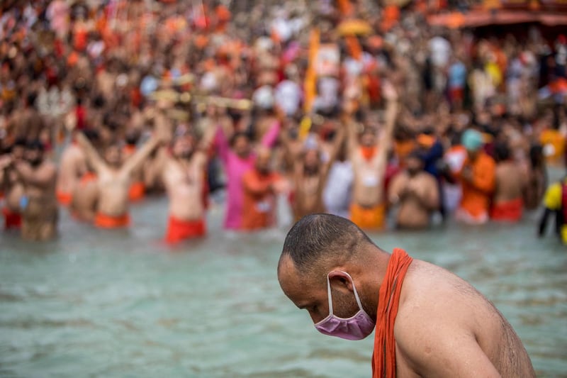 A Sadhu wearing a facemask takes a holy dip in the Ganges river during the ongoing religious Kumbh Mela festival in Haridwar on April 12, 2021. / AFP / Xavier GALIANA
