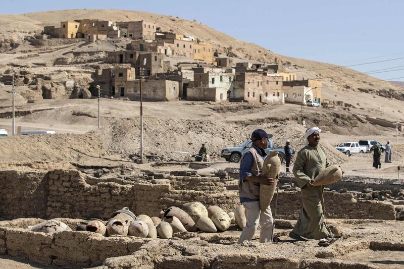 Workers carrying pots found at the site of a 3,000 year old city near Luxor, Egypt, dating to the reign of Amenhotep III. AFP