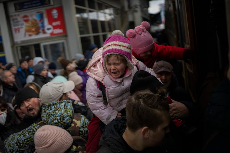 Parents and children struggle to board a train in Lviv. AP