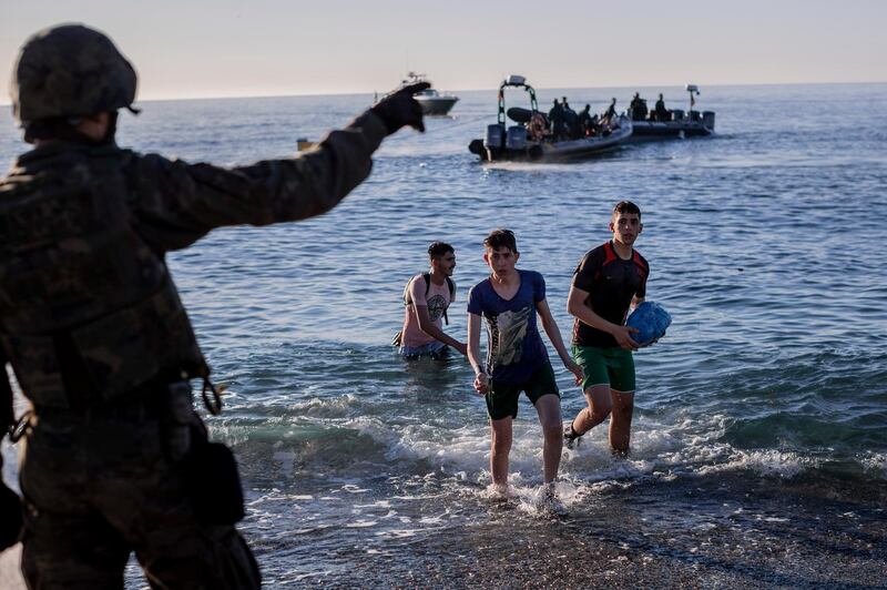 A soldier gestures to migrants as they arrive at Ceuta. AP Photo