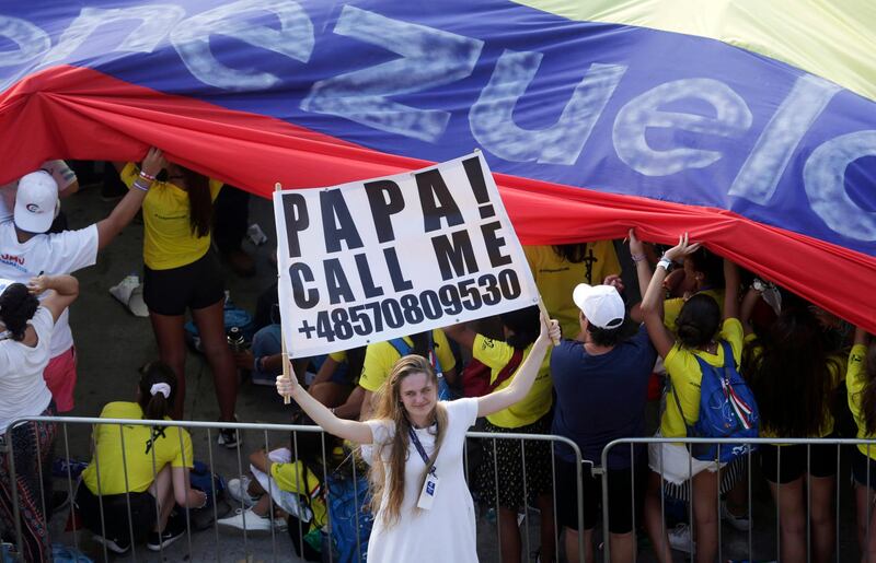 A pilgrim holds a sign asking Pope Francis to call her as she waits for him to arrive to celebrate an outdoor Mass in Panama City. AP Photo