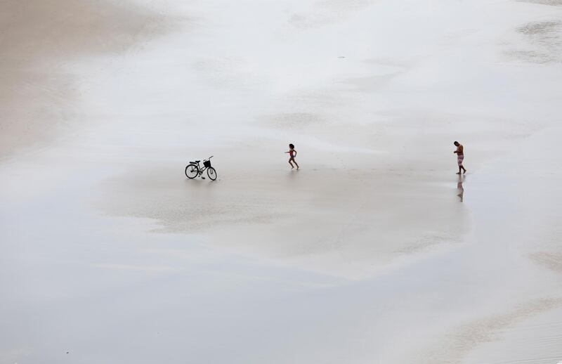 A girl runs towards her bicycle on a beach in Guaruja, Sao Paulo state, Brazil. Reuters