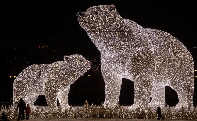 epaselect epa08884003 People walk near huge light sculptures of polar bears installed as part of decoration for the New Year and Christmas holidays in a district of Moscow, Russia, 14 December 2020. Moscow's Mayor Sobyanin said that there will be no massive New Year celebrations in the city this year due to the ongoing pandemic of the COVID-19 disease caused by the SARS-CoV-2 coronavirus.  EPA/SERGEI ILNITSKY