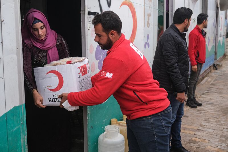 A Turkish Red Crescent employee delivers a box with aid to a displaced Syrian woman at Taybe camp in Sarmada district, near Idlib, north-west Syria. EPA