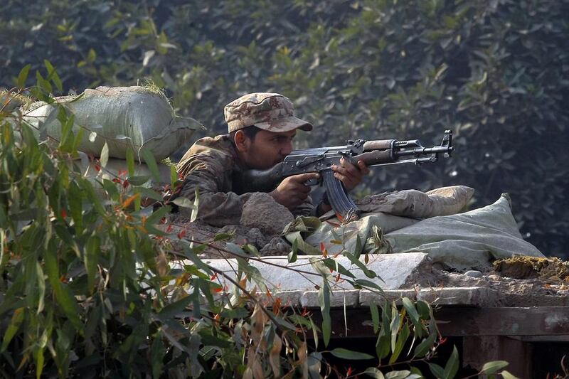A Pakistani army soldier takes position on a bunker close to a school under attack by Taliban gunmen in Peshawar. Mohammad Sajjad / AP Photo