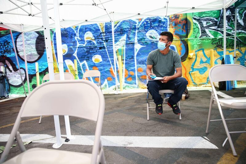 A man sits in the observation area after receiving a Covid-19 vaccine at a mobile bus clinic in Los Angeles, California. The US will miss President Joe Biden's goal of delivering at least one coronavirus vaccine dose to 70 percent of adults by the 4th of July holiday. Getty Images