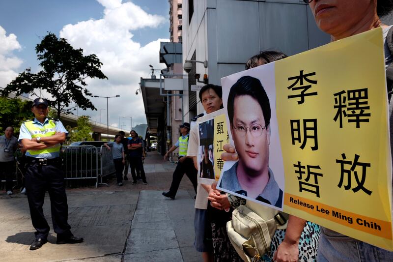 A protester raises a picture of Taiwanese activist Lee Ming-che during a demonstration outside the Chinese liaison office in Hong Kong Monday, Sept. 11, 2017. Lee pleaded guilty to subverting state power in China's first prosecution of a nonprofit worker on criminal charges since Beijing passed a law tightening controls over foreign non-governmental organizations. The words at right reads: "Release Lee Ming-che." (AP Photo/Vincent Yu)
