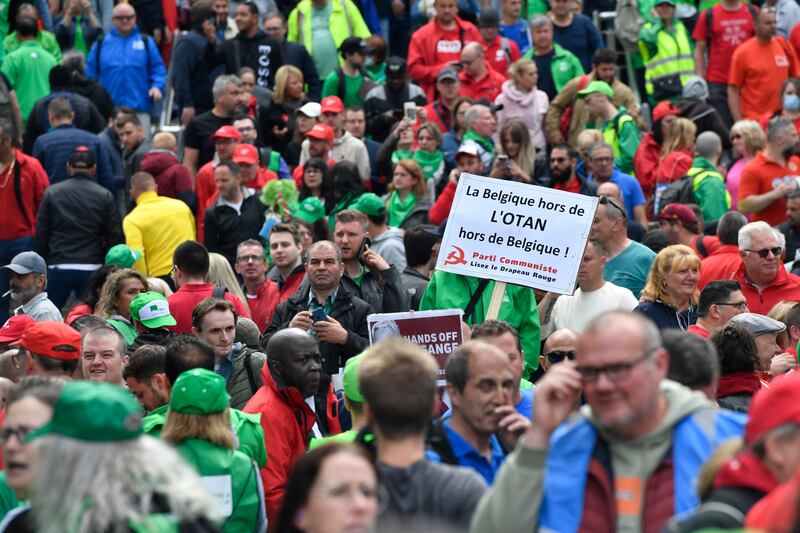 A protester holds a 'Belgium out of Nato' sign on a march with trade union members in Brussels. AP