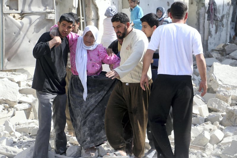 A woman is assisted to walk through the rubble of buildings following a reported air strike by Syrian government forces in the al-Sakhour district of the northern city of Aleppo on April 4, 2014. More than 150,000 people have been killed in Syria since the conflict began in March 2011, a monitoring group said in a new toll released on April 1, 2014.  AFP PHOTO / ALEPPO MEDIA CENTRE / FADI AL-HALABI (Photo by Fadi al-Halabi / AFP)