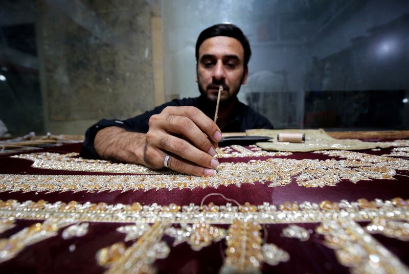 A Pakistani craftsman works on women's embroidered clothes before Eid Al Fitr in Peshawar, Pakistan. EPA