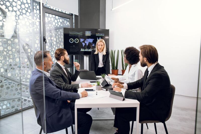 2DMY5RE Board of diverse multiethnic directors business people at annual meeting in office room, listening mature blond lady and discussing work results. TV