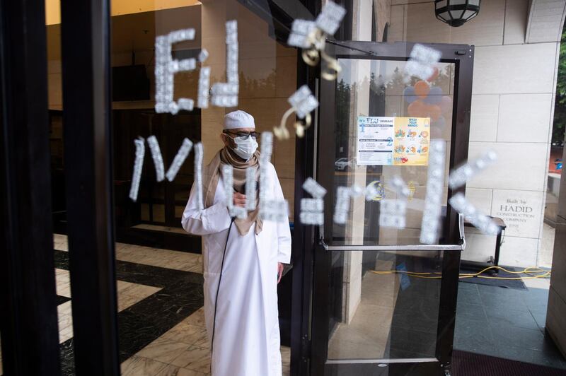 Joint supervisor Mohmed El Idrissi offers supplication behind a glass door that reads 'Eid Mubarak' during the Eid Al Fitr in Falls Church, Virginia, US. EPA