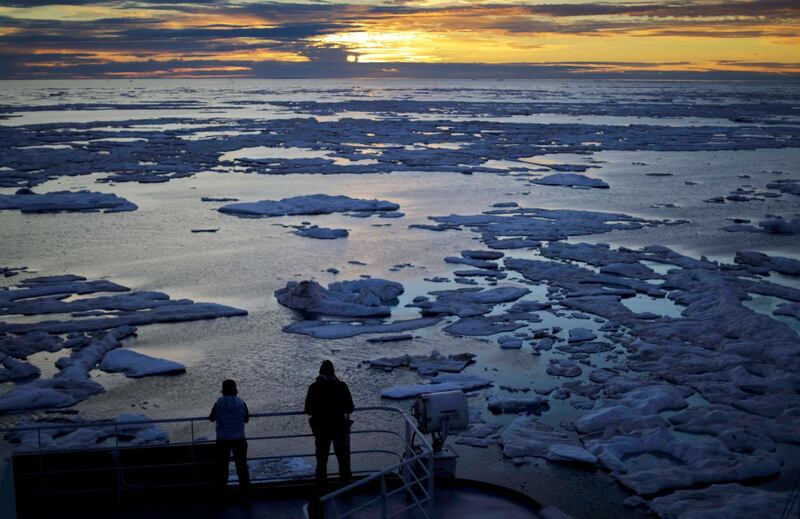 ADVANCE FOR USE MONDAY, JUNE 18, 2018, AT 3:01 A.M. EDT AND THEREAFTER-FILE - In this July 21, 2017 file photo, researchers look out from the Finnish icebreaker MSV Nordica as the sun sets over sea ice in the Victoria Strait along the Northwest Passage in the Canadian Arctic Archipelago. Studies show the Arctic is heating up twice as fast as the rest of the planet. Scientists are concerned because impacts of a warming Arctic may be felt elsewhere. (AP Photo/David Goldman, File)