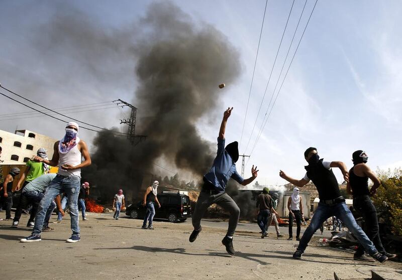 Palestinian protesters throw stones during clashes with Israeli security forces in the West Bank city of Hebron. (Abed Al Hashlamoun / EPA)