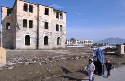 An Afghan woman walks with her children past destroyed buildings in Kabul, 02 February 2006.   A major donors' conference for Afghanistan has ended with pledges totalling 10.5 billion USD (8.7 billion euros) to rebuild the strategic Central Asian nation over the next five years. Afghan Finance Minister Anwar-ul-Haq Ahady hailed the outcome of the two-day gathering of 70-odd nations, saying the funds would help his destitute country "realise our development strategy" after many years of bloody conflict. AFP PHOTO/SHAH Marai (Photo by SHAH MARAI / AFP)