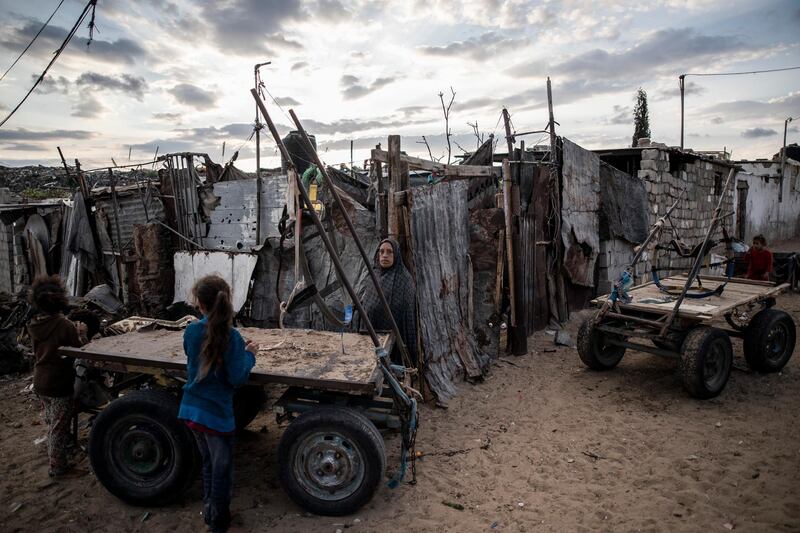A Palestinian woman stands next to her house in a slum on the outskirts of Khan Younis Refugee Camp, in the southern Gaza Strip. AP Photo