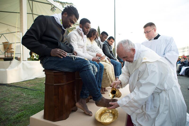 In this handout picture released by the Vatican Press Office, Pope Francis performs the foot-washing ritual at the Castelnuovo di Porto refugees center near Rome on March 24, 2016. Pope Francis washed the feet of 11 young asylum seekers and a worker at their reception centre to highlight the need for the international community to provide shelter to refugees. - Several of the asylum seekers, one holding a baby in her arms, were reduced to tears as the 79-year-old pontiff kneeled before them, pouring water over their feet, drying them with a towel and bending to kiss them. (Photo by STR / OSSERVATORE ROMANO / AFP) / RESTRICTED TO EDITORIAL USE - MANDATORY CREDIT "AFP PHOTO / OSSERVATORE ROMANO" - NO MARKETING NO ADVERTISING CAMPAIGNS - DISTRIBUTED AS A SERVICE TO CLIENTS