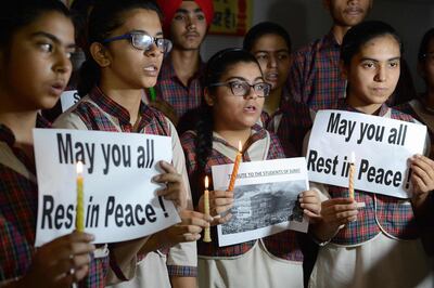 Indian students hold candles as they pay tribute to the students died in a fire in a building in India housing a college in Surat, at a school in Amritsar on May 25, 2019.  At least 19 students -- most of them female -- died on May 24 in a fire at an Indian building housing a college, officials said, as images showed people jumping to escape the blaze. / AFP / NARINDER NANU
