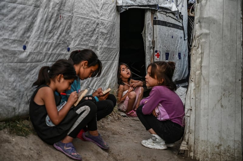Childs are pictured in a improvised tents camp near the refugee camp of Moria in the island of Lesbos on June 21, 2020. - Greece's announcement that it was extending the coronavirus lockdown at its migrant camps until July 5, cancelling plans to lift the measures on June 22, coincided with World Refugee Day on June 27, 2020. (Photo by ARIS MESSINIS / AFP)