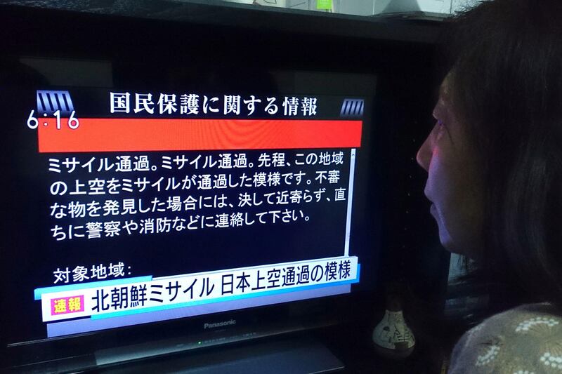 A woman looks at a television news displaying warnings via the "J-alert" system in Tokyo on August 29, 2017, following a North Korean missile test that passed over Japan. Kazuhiro Nogi / AFP