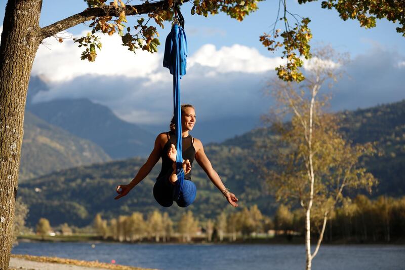 Woman doing pose of aerial yoga using hammock outdoors. Saint-Gervais, France. (Photo by: Godong/UIG via Getty Images)