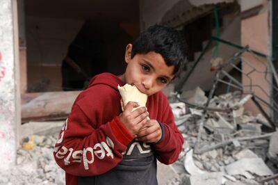 A child eats a sandwich as he stands in front of a building damaged by Israeli bombardment in Rafah in the southern Gaza Strip. AFP
