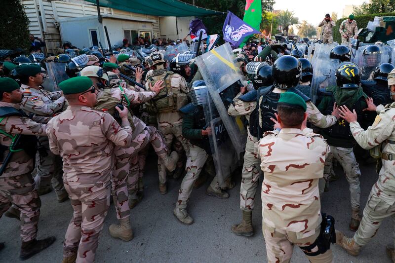 Riot police scuffle with demonstrators protesting outside the Swedish embassy in Baghdad over the burning of a Quran in Stockholm. AFP

