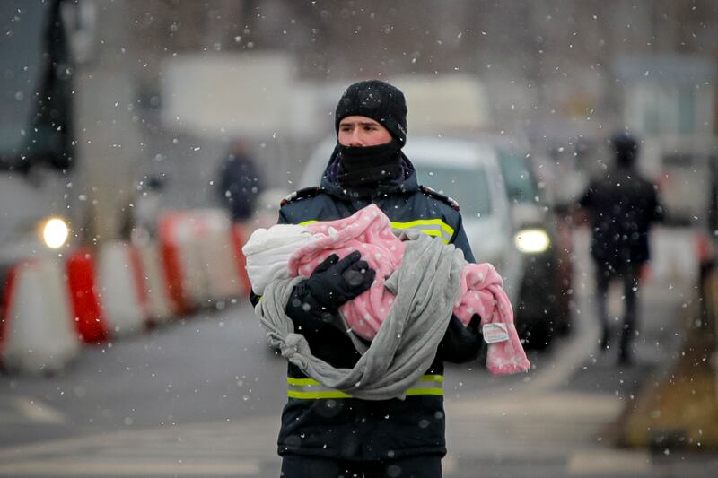 A firefighter holds the baby of a Ukrainian refugee at the border in Romania. AP