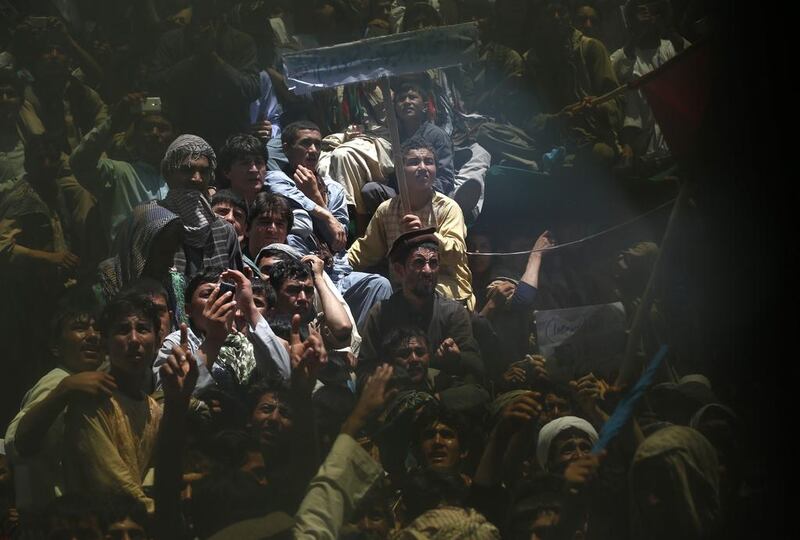 Supporters of Afghan presidential candidate Abdullah Abdullah are seen through a broken window during an election campaign in Qala I Naw, capital of Badghis province. Mohammad Ismail / Reuters