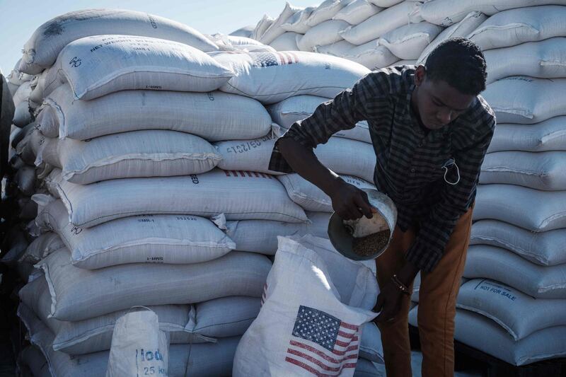 A man shares food contribution by USAID to Ethiopian refugees who fled the Tigray conflict at Village Eight transit centre near the Ethiopian border in Gedaref, eastern Sudan, on December 2, 2020.   / AFP / Yasuyoshi CHIBA
