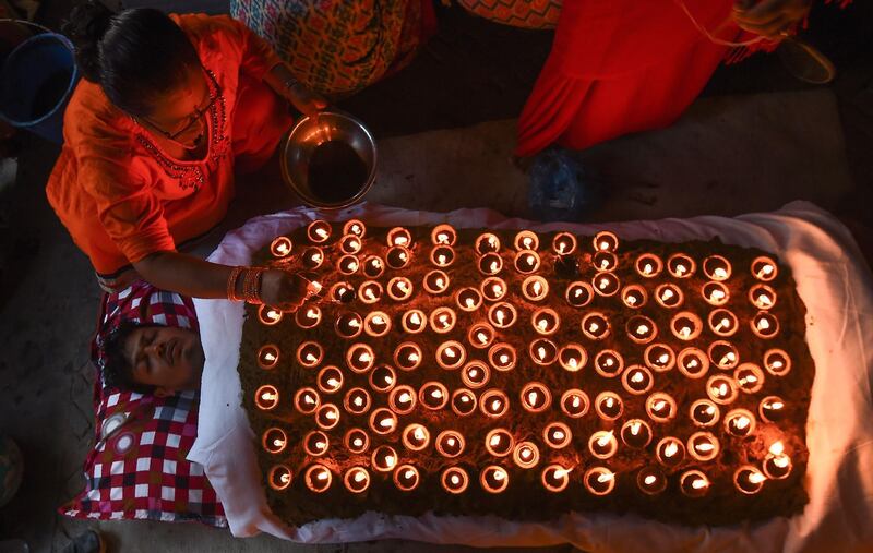 A Hindu devotee lies in a bed covered by 108 lit oil lamps on the tenth day of Dashain in Bhaktapu, Kathmandu. Prakash Mathema / AFP